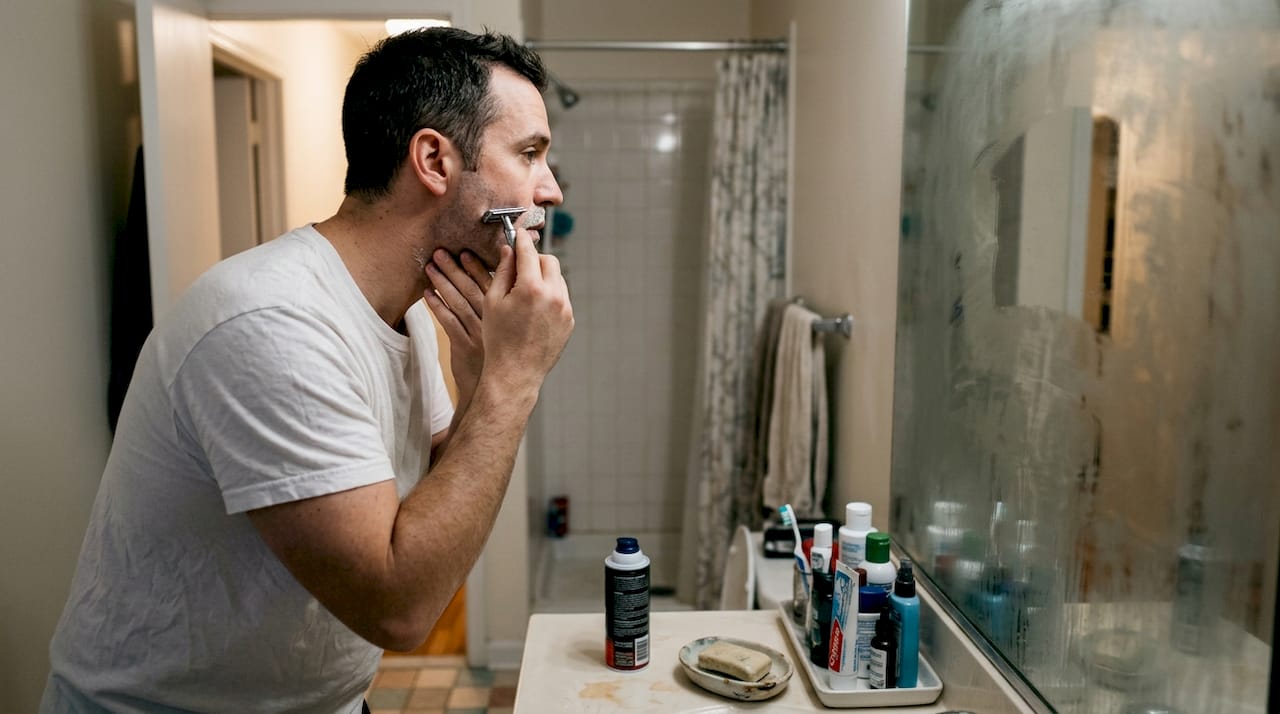 Man shaving in everyday apartment bathroom