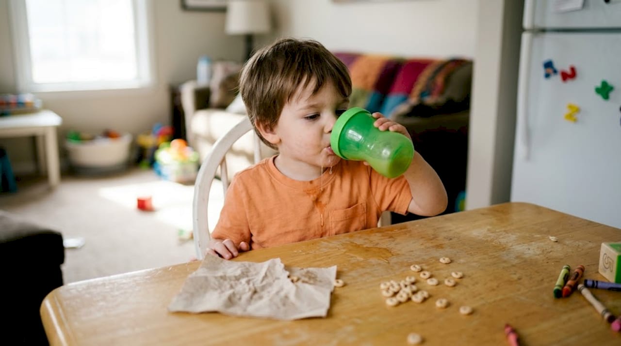 Child using sippy cup and making a mess