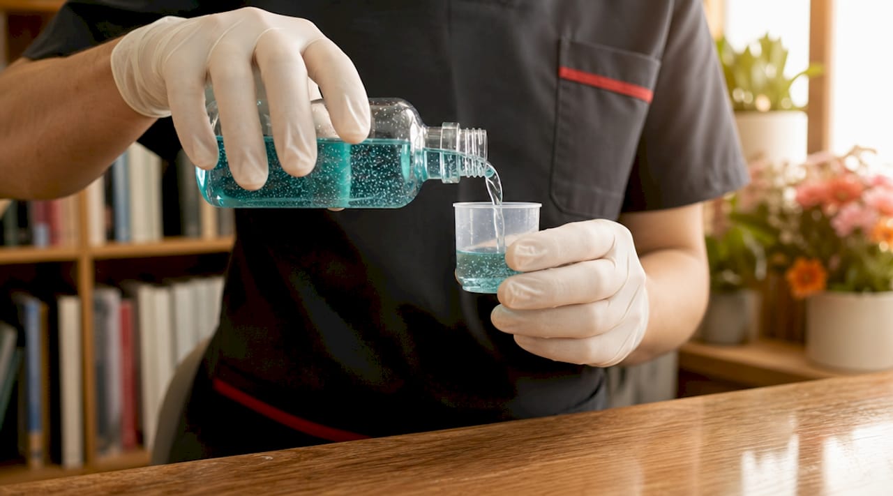 Dentist holding mineral mouthwash bottle close-up