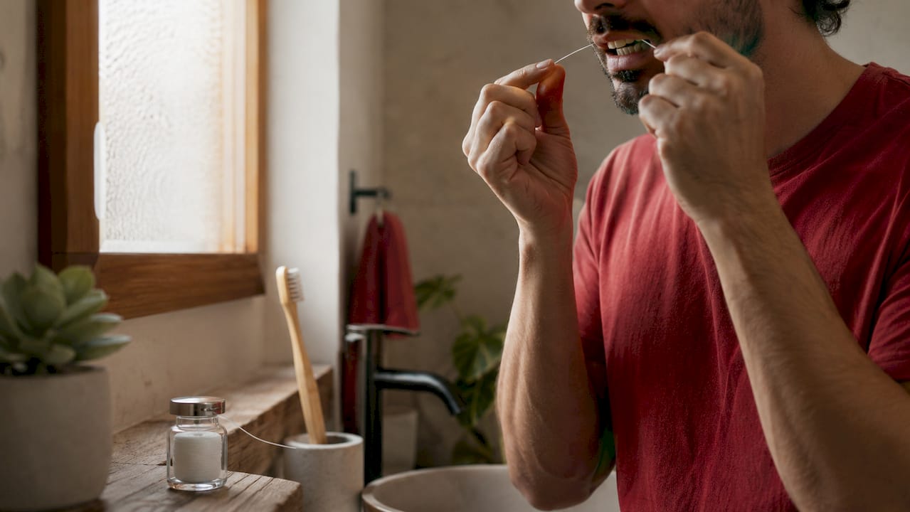 Hands flossing teeth to remove plaque for gum health
