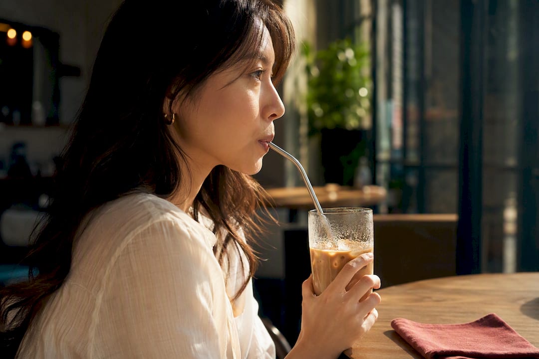 Person sipping iced coffee through a straw
