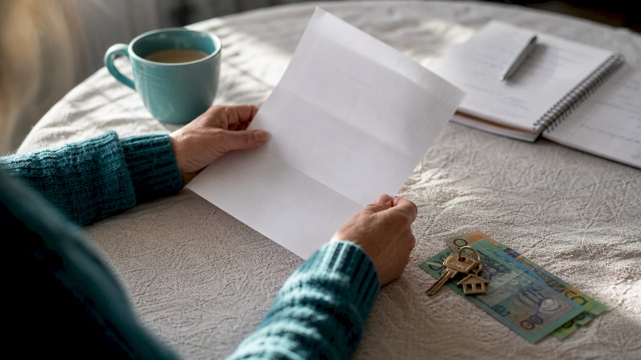 Hands holding property title with house keys on desk