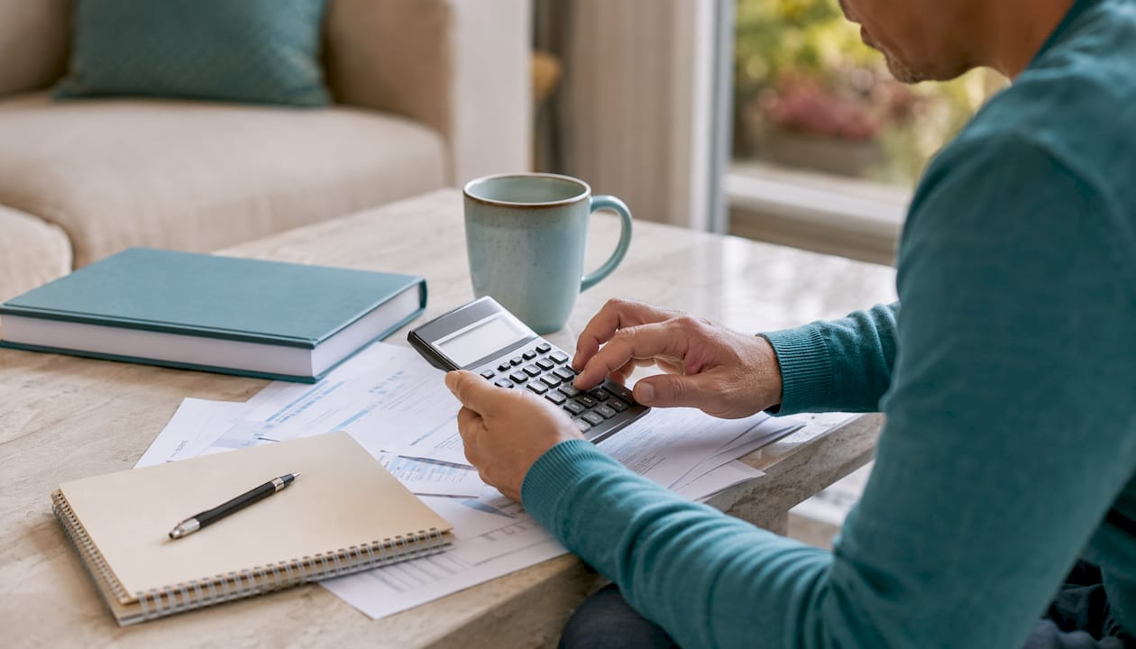 Hands pressing calculator keys at kitchen table
