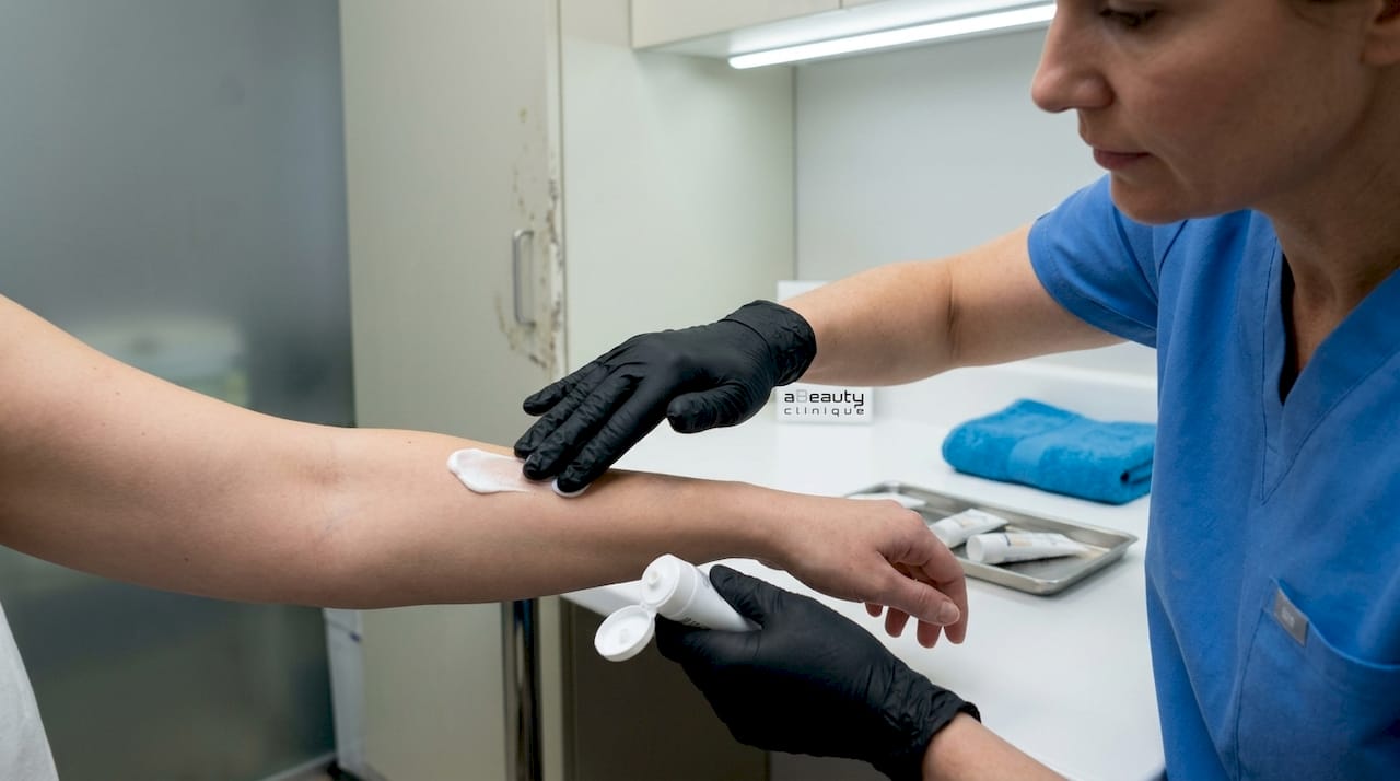 Medic dermatolog care aplică o cremă pentru estomparea petelor pigmentare