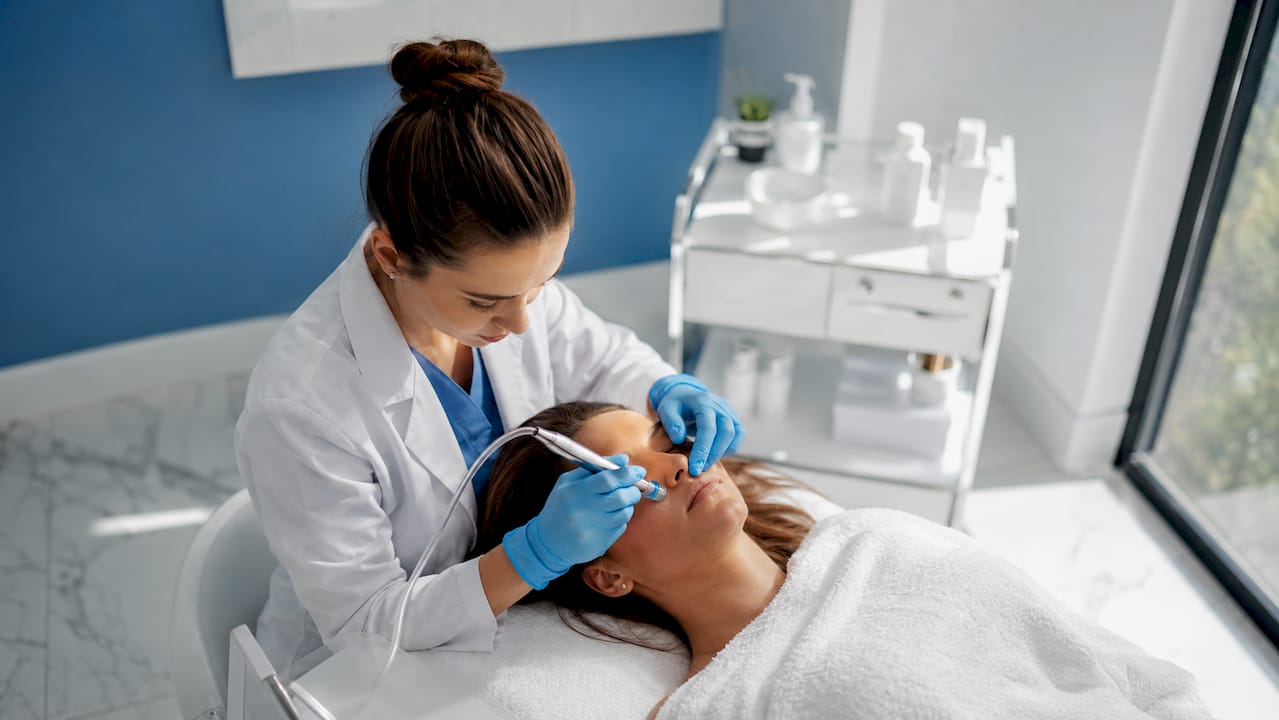 Medicul dermatolog efectuează procedura de microneedling pentru îmbunătățirea aspectului pielii.