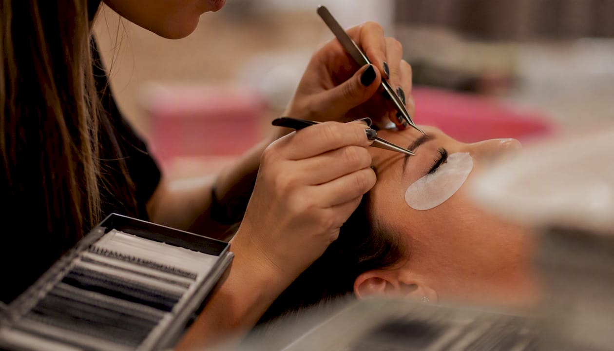 Una professionista delle ciglia sta applicando le extension in un elegante centro benessere, creando un look impeccabile in un ambiente rilassante e curato.