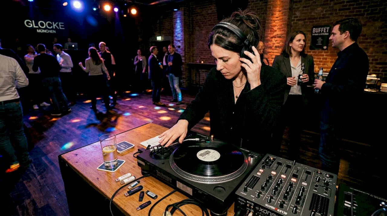 10 Tipps für Messepartys in München: Kreative Ideen und DJ-Erfolg 2 Ein DJ sorgt auf einer Veranstaltung in München für Stimmung, während sich die Gäste untereinander austauschen und ins Gespräch kommen.