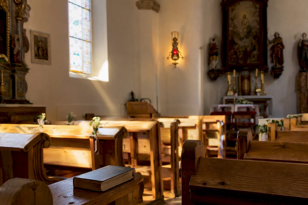 Eine leere Holzbank in einer österreichischen Kirche.