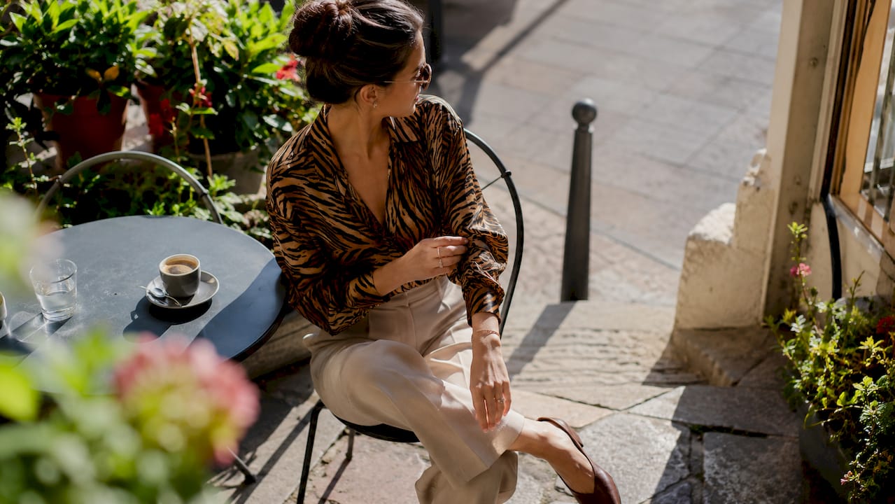 Woman wearing elegant tiger print blouse indoors