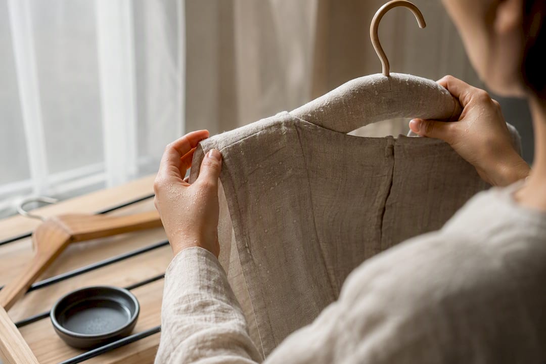 Hands reshaping damp linen garment