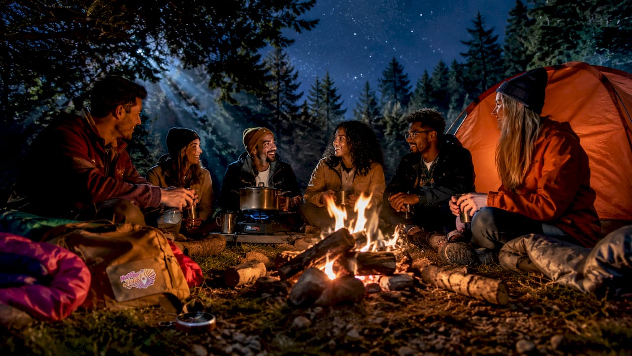 Group camping and cooking around fire in forest