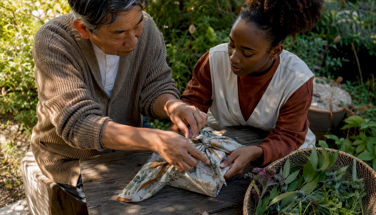 Hands learning furoshiki wrapping technique on wooden table