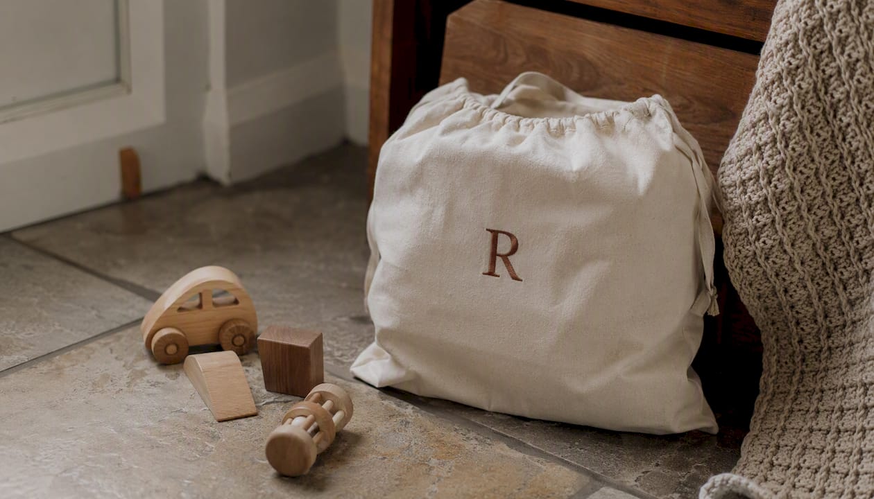 Toy bag with embroidered initial on wooden floor