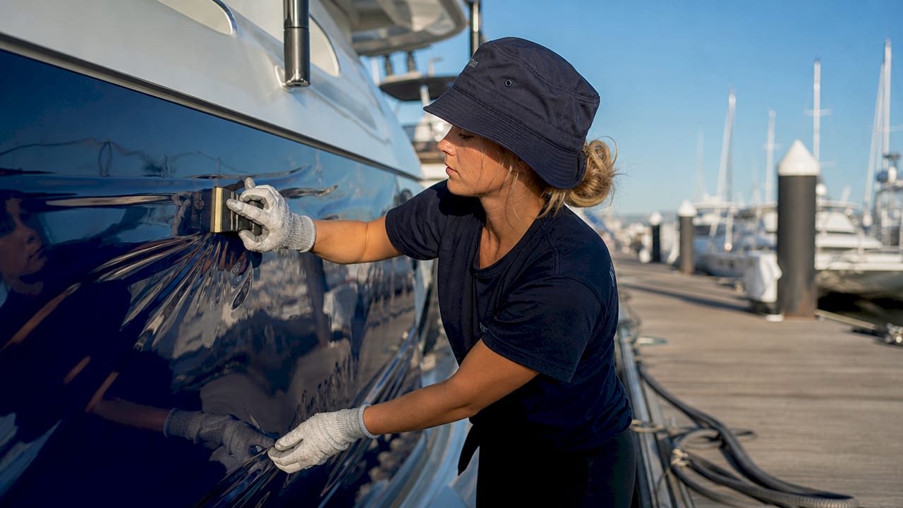 Technician applying navy blue vinyl wrap on yacht