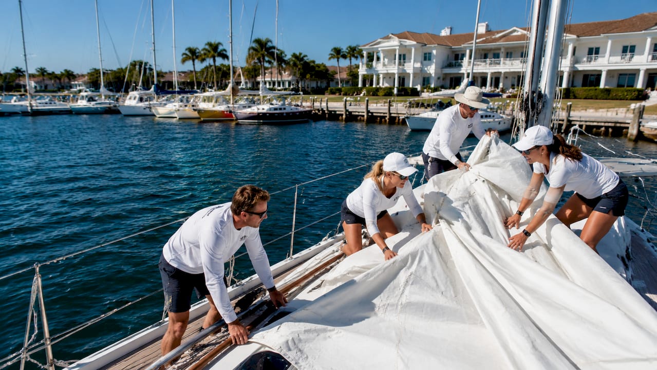 Group preparing sailboat at traditional Palm Beach sailing club outdoors.
