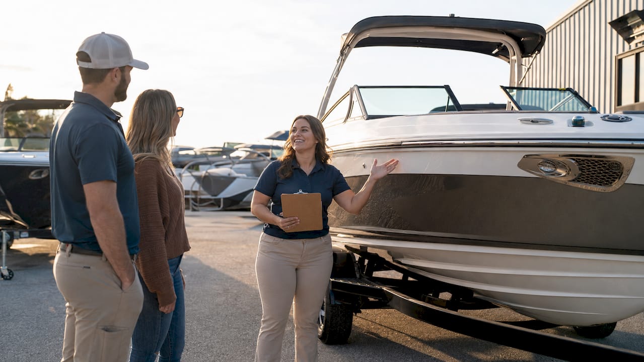 Boat saleswoman showing boat to customers outdoors