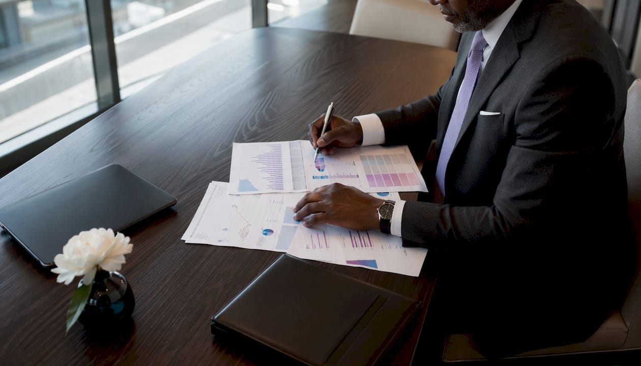 Close-up hands annotating sales territory documents on luxury desk