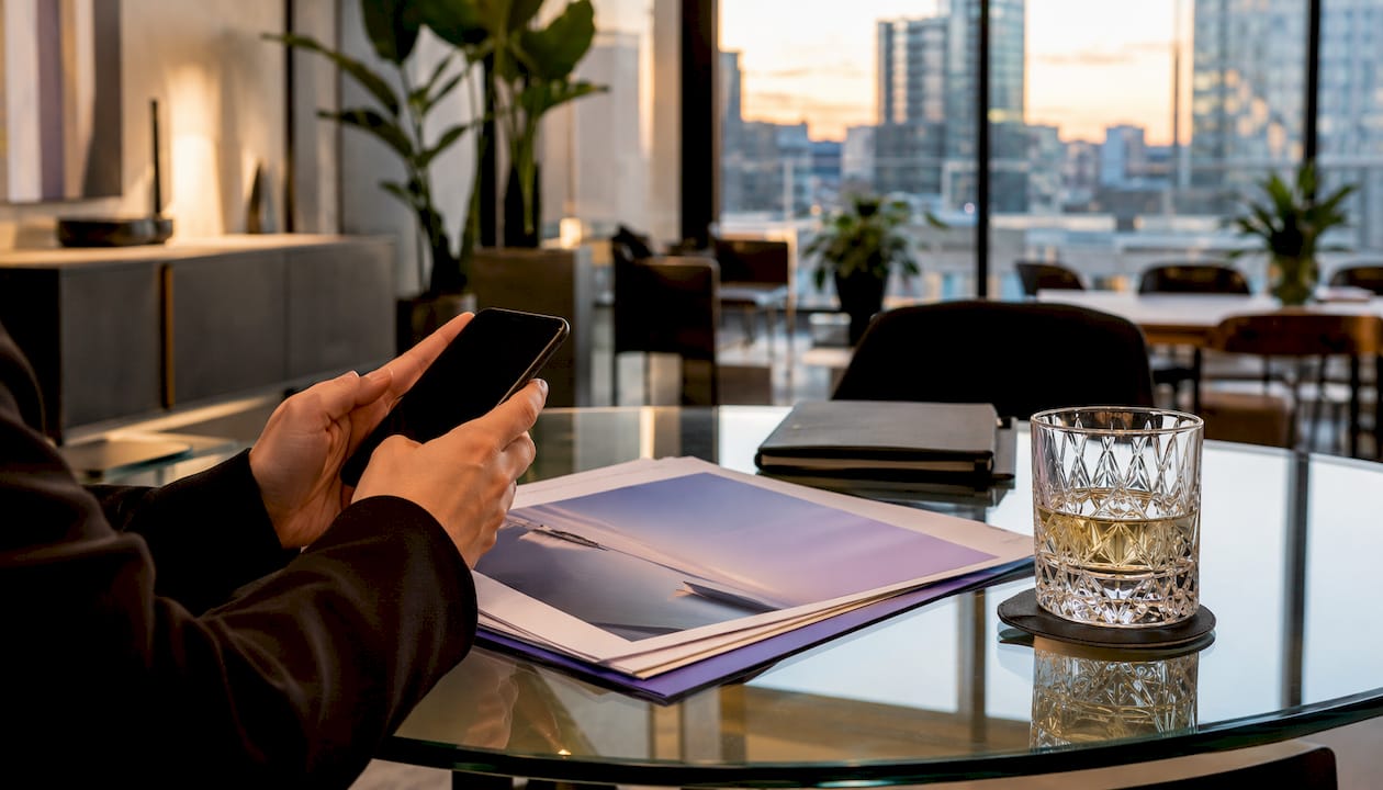 Hands holding phone over marketing reports in agency