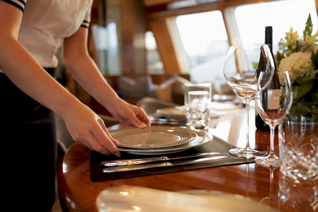 Hands setting yacht dining table rehearsal