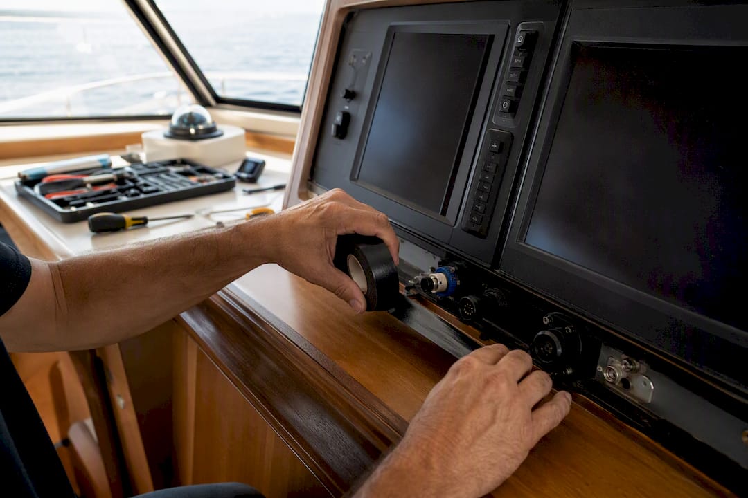 Hands taping yacht electronics panel seams