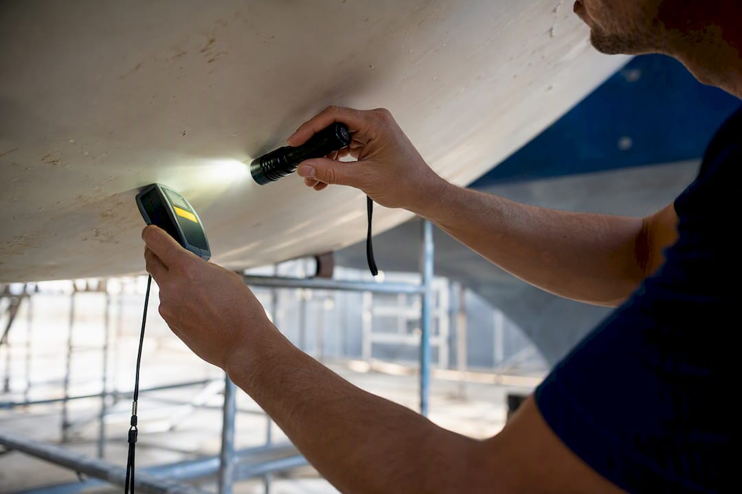 Surveyor inspecting yacht hull with tools