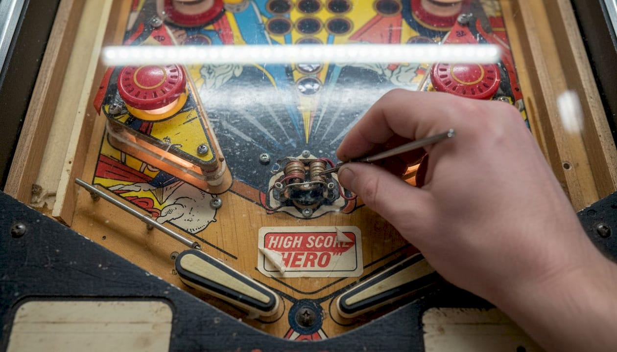 Technician adjusting pinball machine bumpers