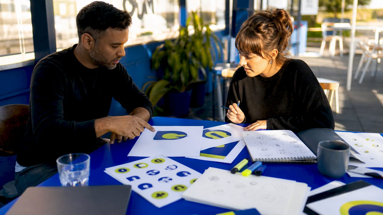 The role of negative space in graphic design 2 Designers discussing negative space logos at table