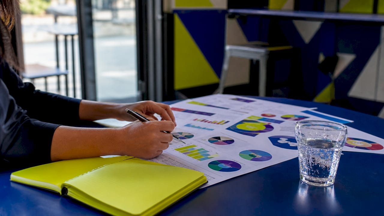 Close-up of hand reviewing customer data sheets