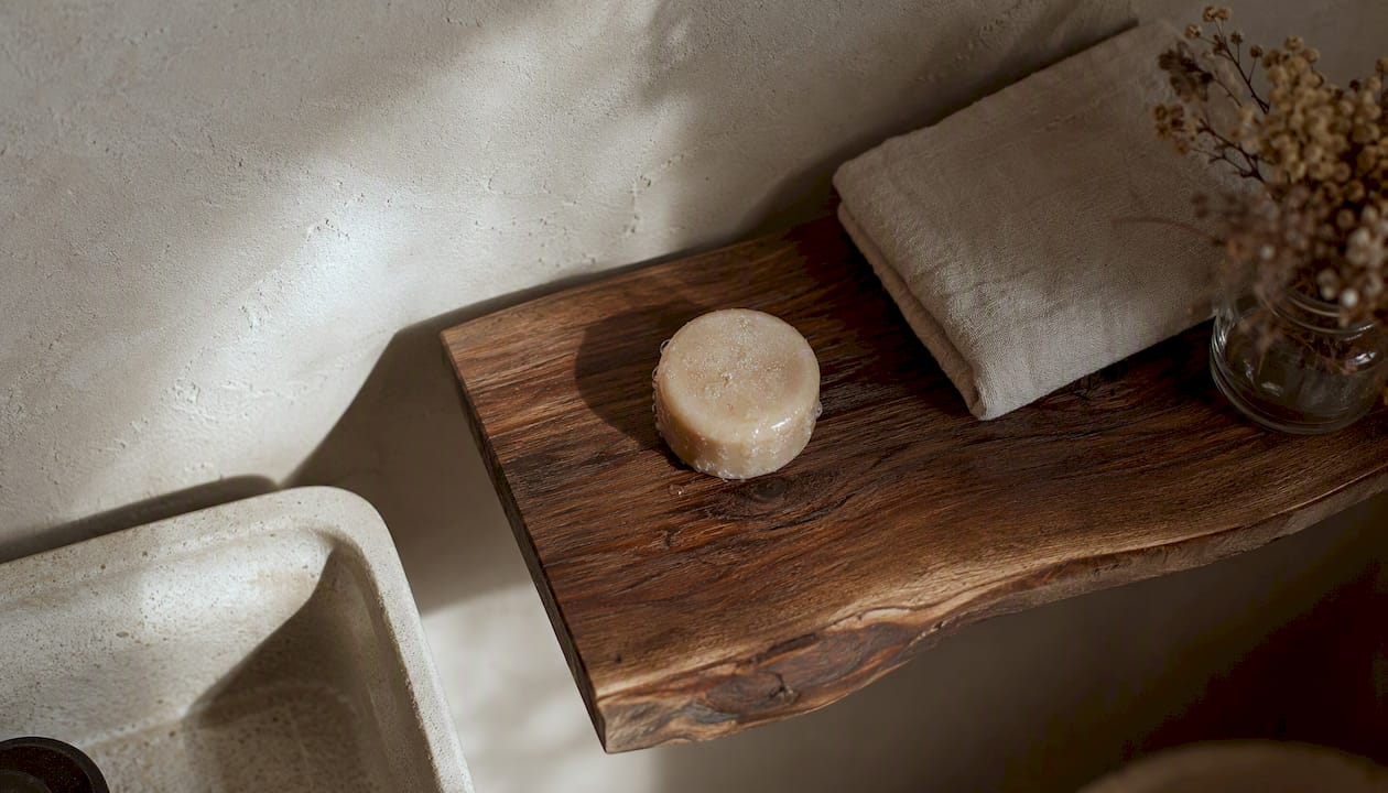 Een shampoo bar ligt te drogen op een houten rekje, met een handdoek ernaast.