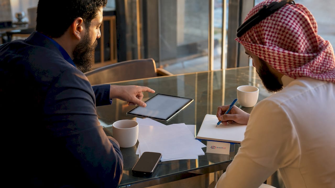 Two professionals collaborating using laptop and tablet