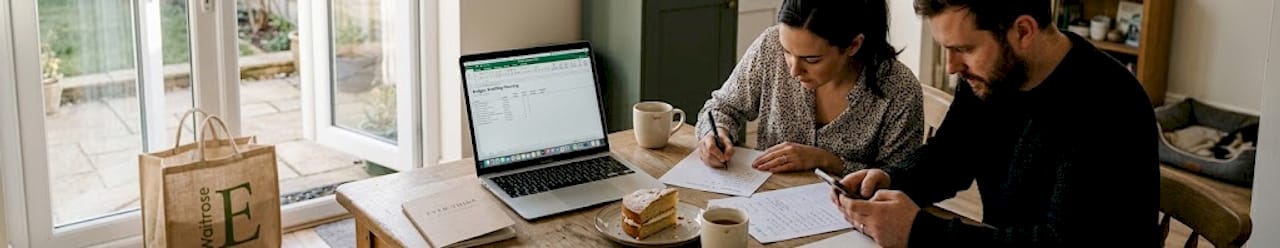 British couple planning wedding timeline at kitchen table