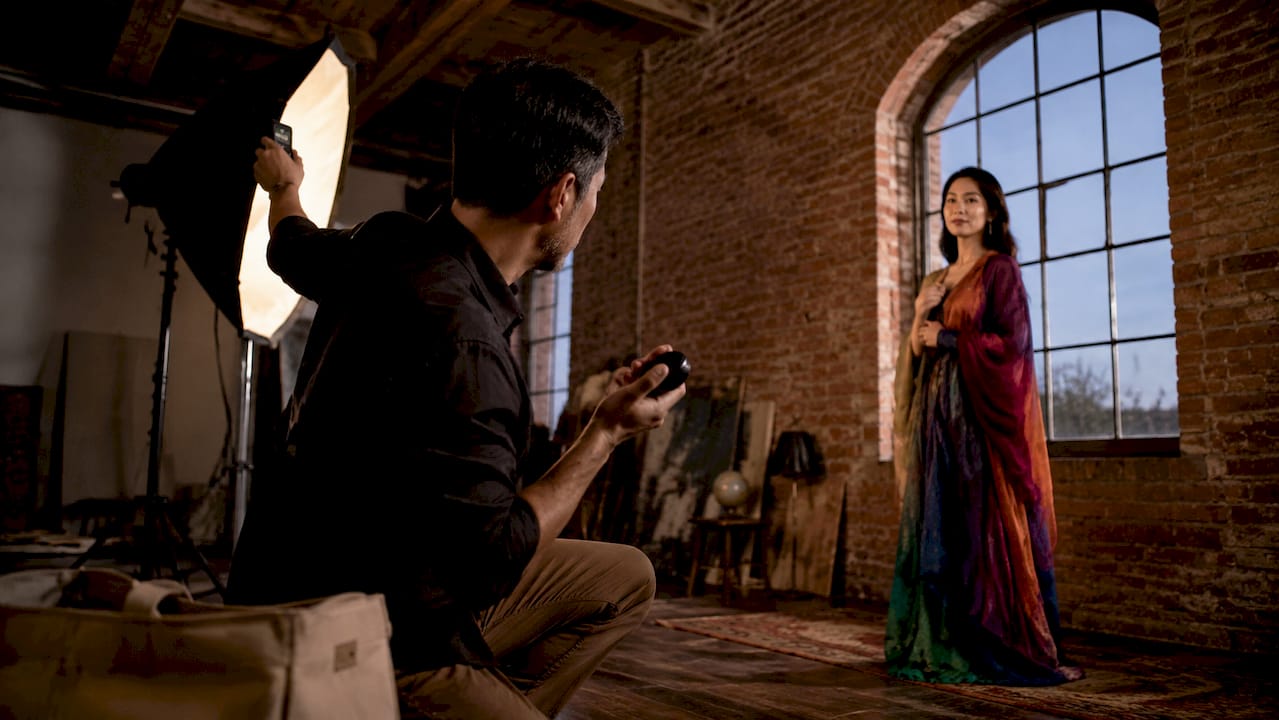 Photographer adjusting softbox light with seated model