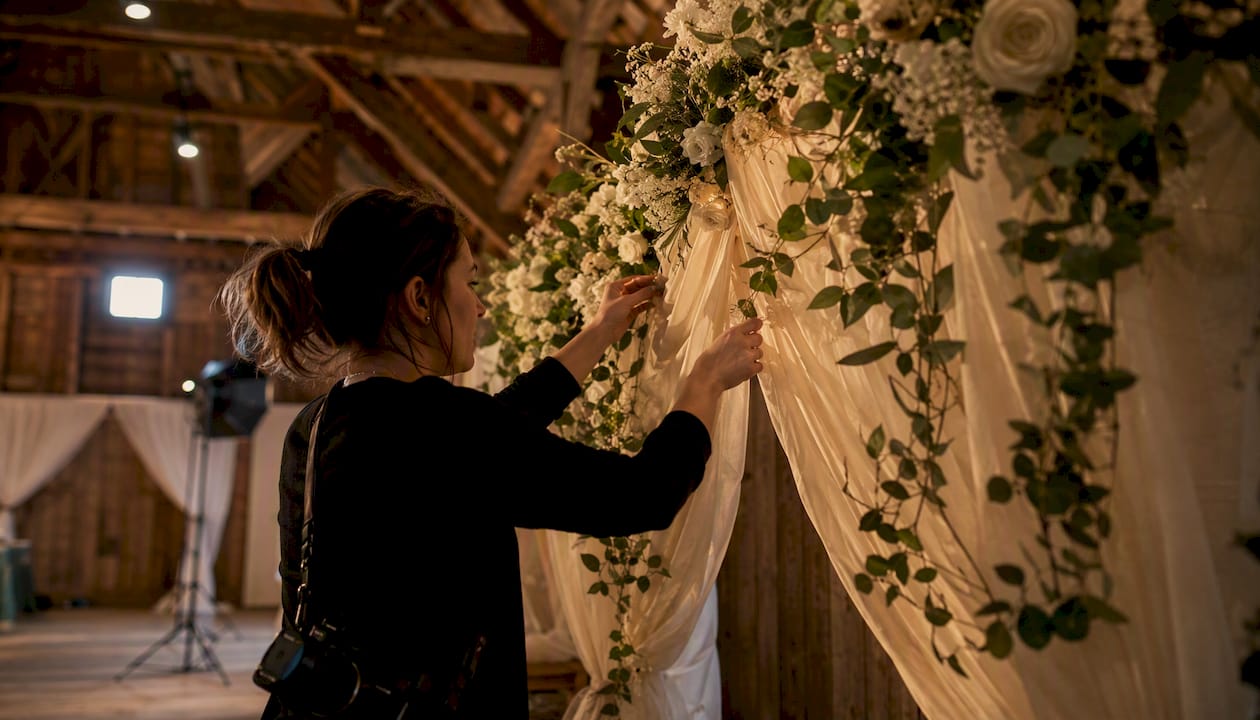 Photographer adjusting wedding photo backdrop indoors