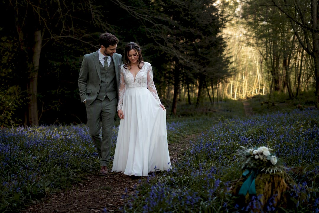 Newlyweds walking through a bluebell wood