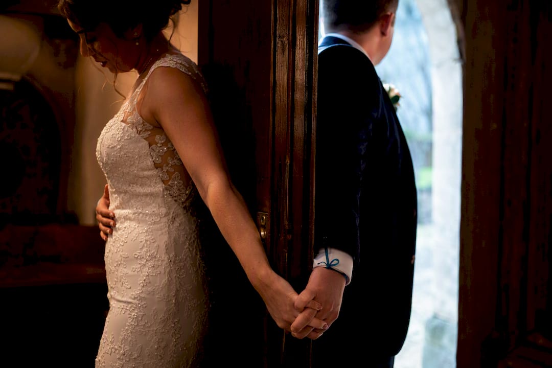 Couple holding hands across wedding doorway