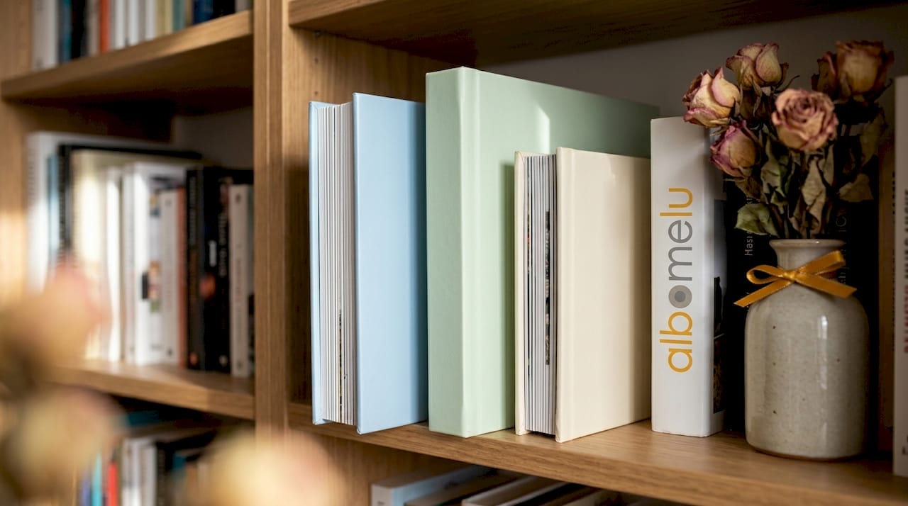 Pe raft se află trei albume foto, fiecare cu dimensiuni diferite.