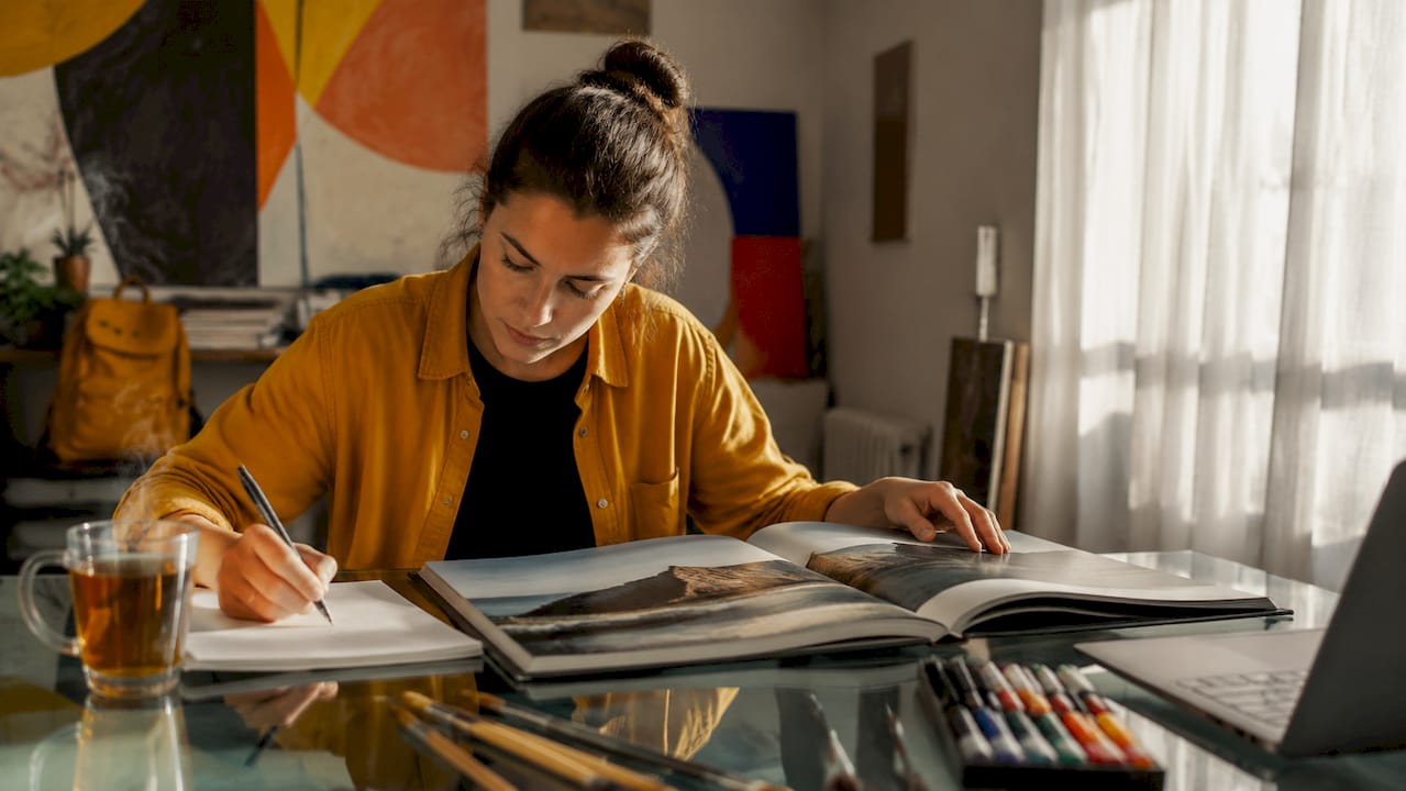 Un designer analizează cu atenție macheta unui album foto la birou, verificând fiecare detaliu înainte de versiunea finală.