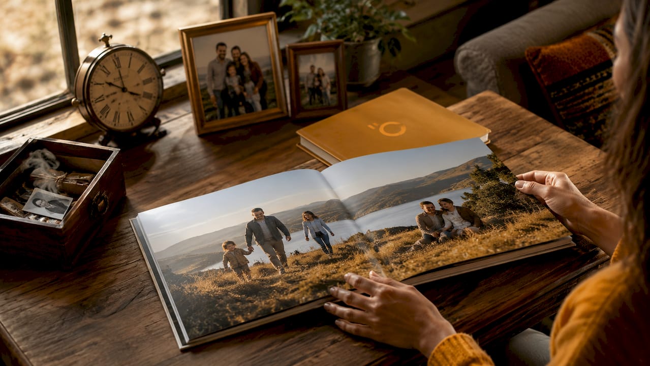 Mâini răsfoind cu grijă un album foto premium, cu pagini care se așază perfect la orizontală