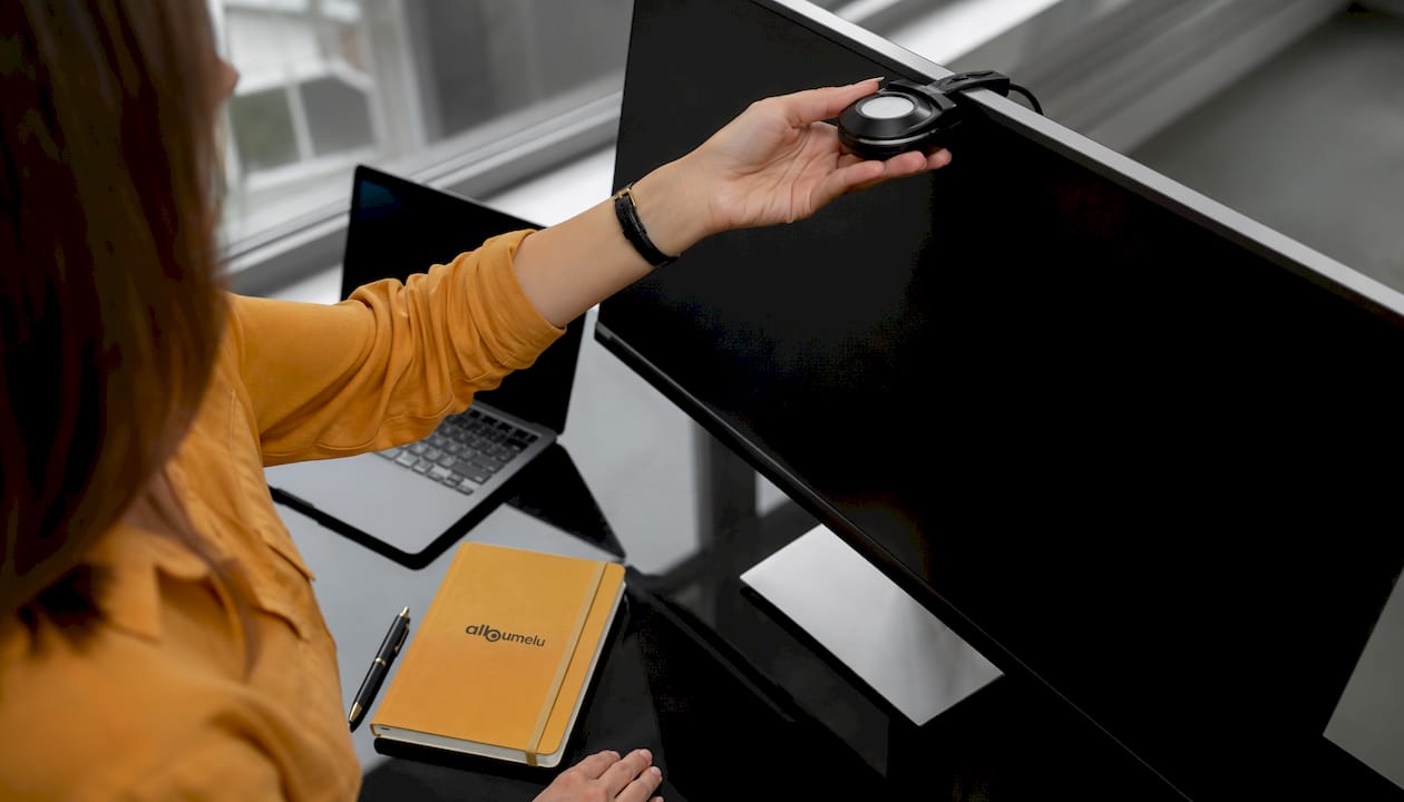 Mâini care reglează un colorimetru pe un monitor, într-un birou