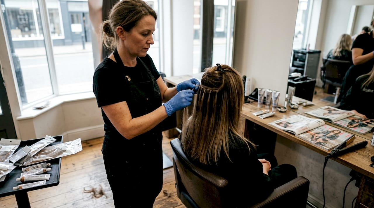Hairstylist applies glue extensions at salon