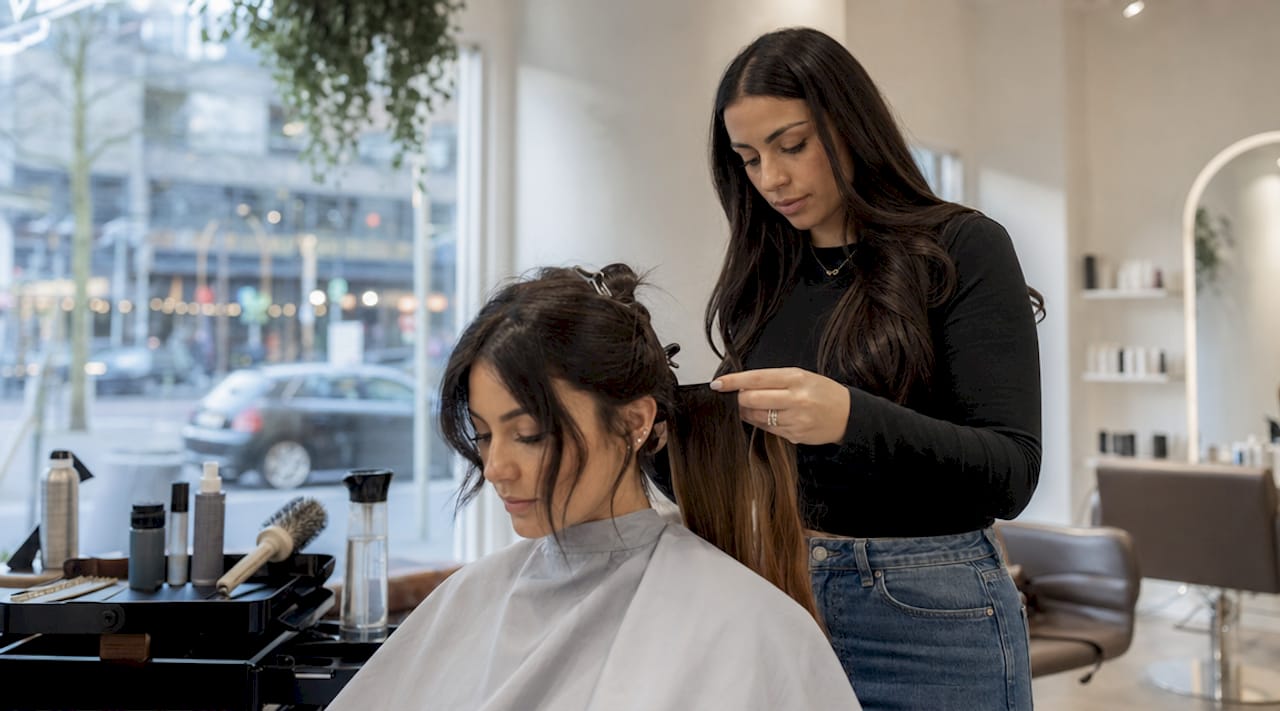 Hairstylist fitting hair extensions in salon