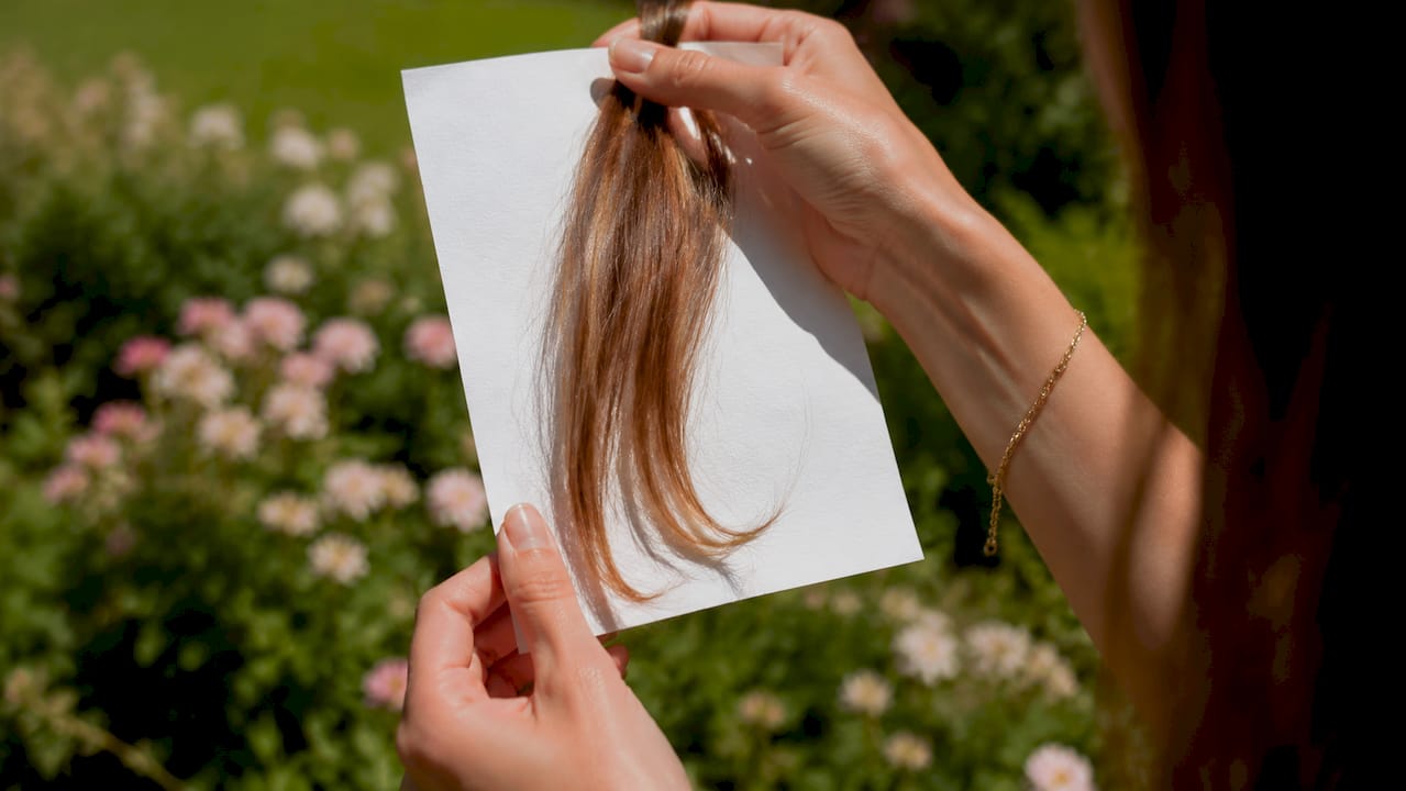 Hands testing hair undertone with white paper