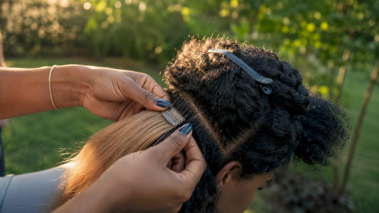 Hands clipping in hair extensions outdoors
