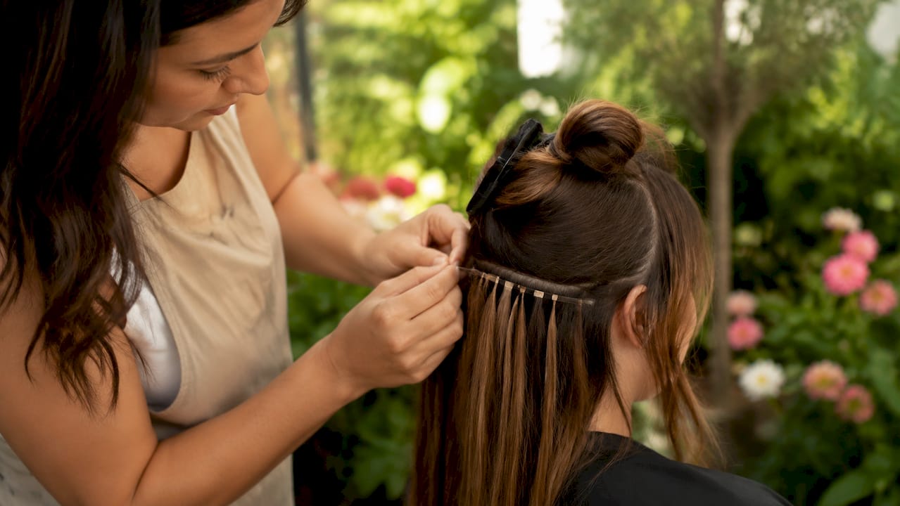 Close-up of hairdresser blending hair extensions