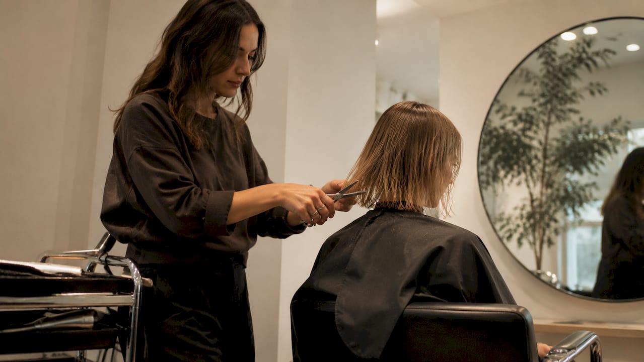 Hairstylist cutting fine hair blunt layers in salon