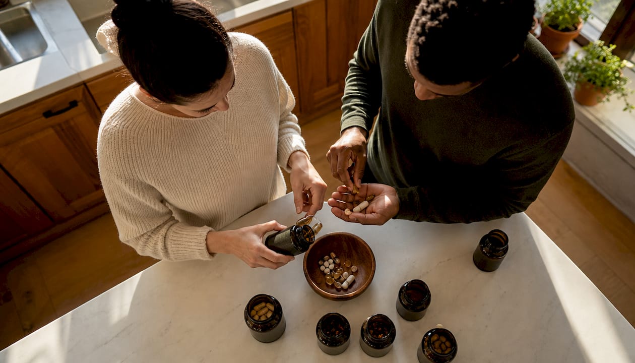 Hands holding various supplement capsules and tablets