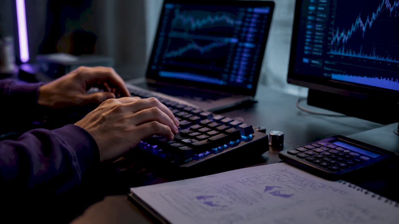 Close-up hands coding financial models on keyboard
