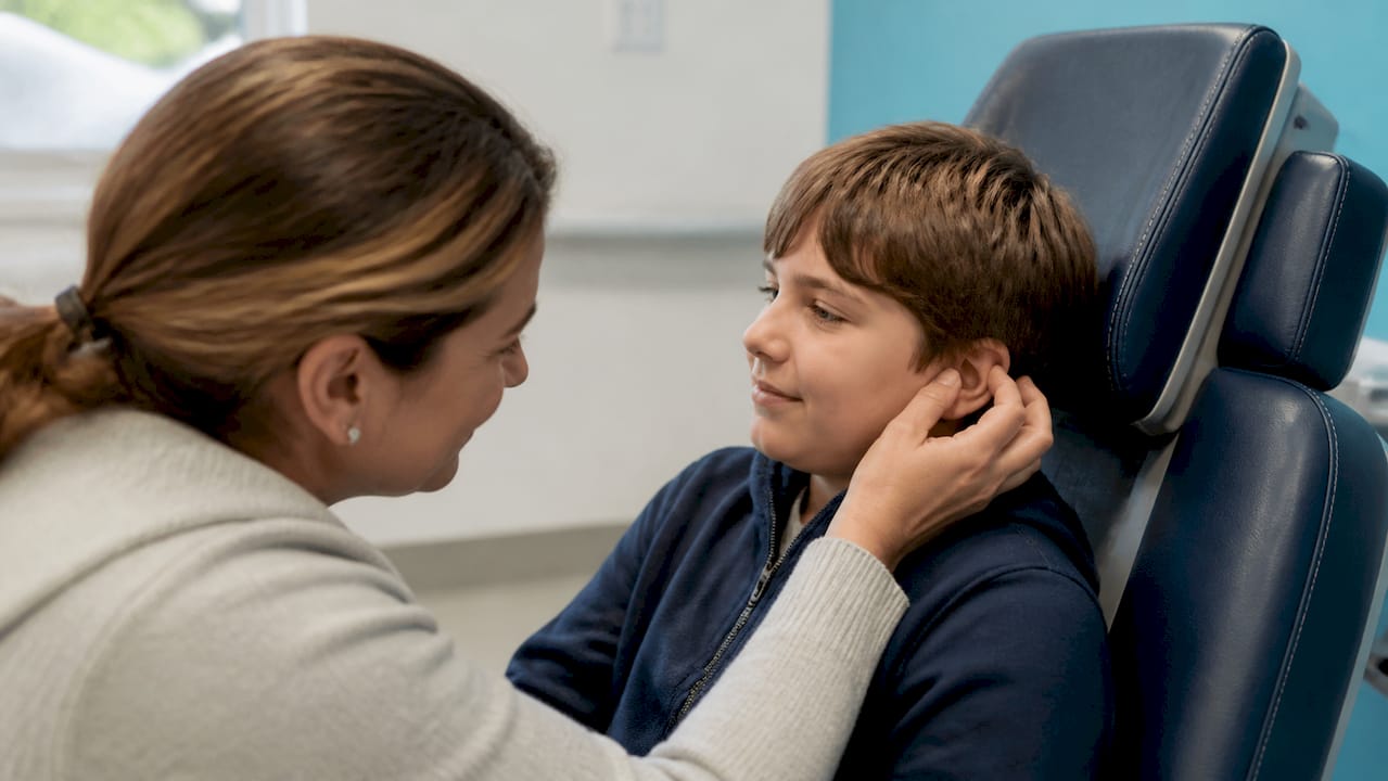 Parent touching autistic child's outer ear