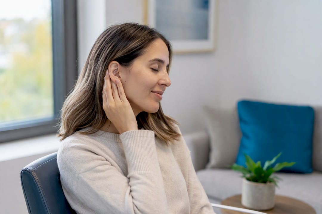 Patient gently touching outer ear in clinic