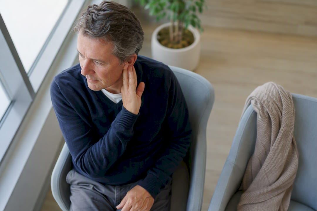 Patient touching outer ear gently in clinic